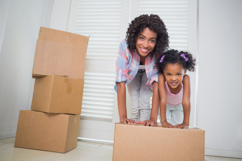 Cute daughter unpacking moving boxes with her mother in their new home-3