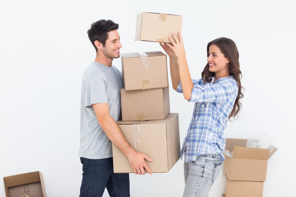 Happy woman giving boxes to her husband while they are moving