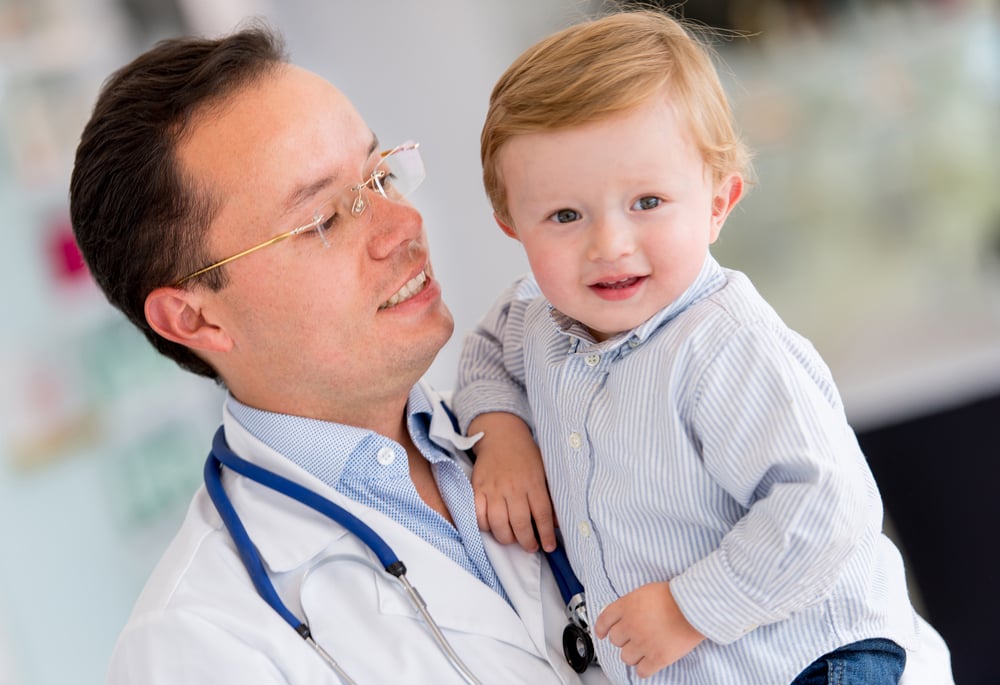 Little boy at the hospital being held by a doctor