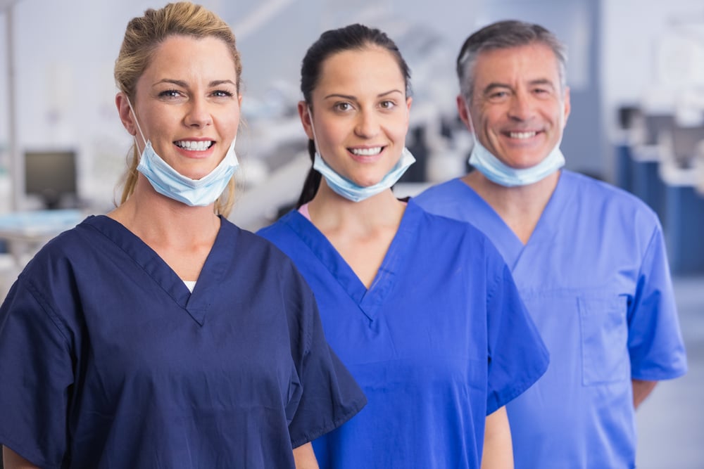 Portrait of smiling co-workers standing in a line in dental clinic