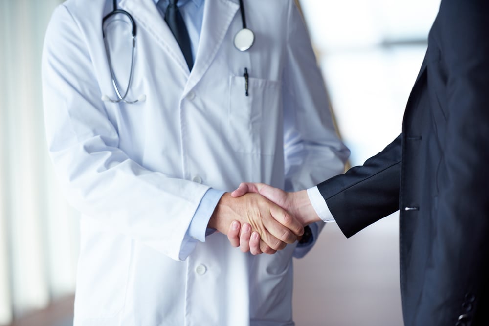 doctor handshake with a patient at doctors bright modern office in hospital-1